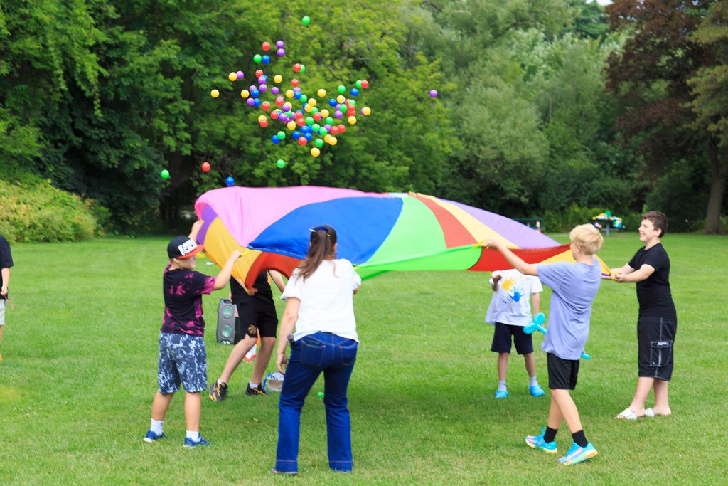 Creative Inclusion participants playing with a colourful parachute outdoors